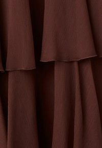 Tissu marron foncé à couches avec une texture subtilement côtelée formant des plis verticaux doux et superposés.