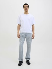 Balti trumpomis rankovėmis marškinėliai derinami su šviesiai mėlynomis tiesiomis kelnėmis ir juodais odiniais batais. Paprastas, kasdienis dizainas su laisvu siluetu.