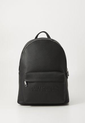Zwarte leren rugzak met een ronde vorm, gestructureerd oppervlak, voorvak met rits en een geëmbosseerd logo op de onderzijde van de voorkant. Accenten van zilverkleurig hardware.