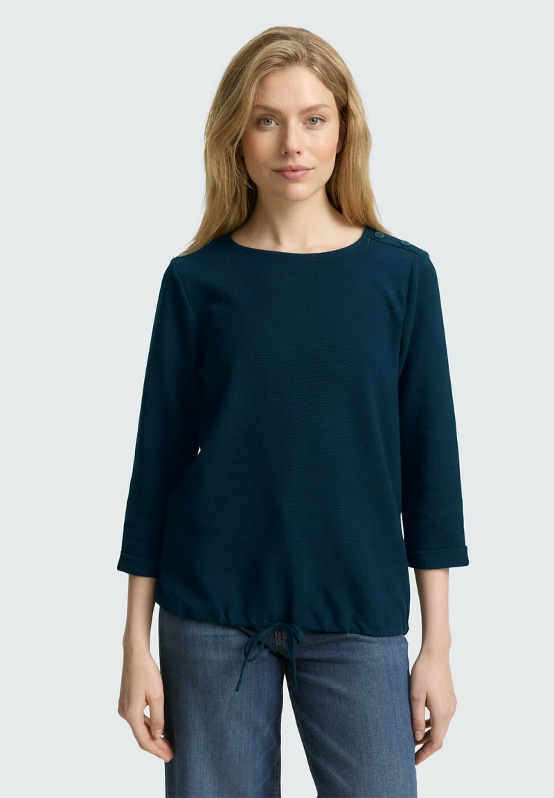 Marineblaues Langarmoberteil mit rundem Halsausschnitt, gerafft Saum mit verstellbarem Kordelzug und Knopfdetails an der Schulter. Lässiges Design.