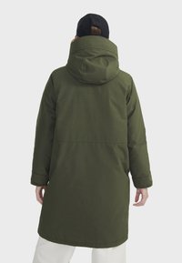Parka olive verte avec capuche, présentant une coupe droite, des manches longues et une texture lisse. Aucune quincaillerie ou motif visible.