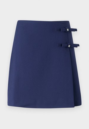 Marineblauwe wikkelrok met een textuurafwerking, voorzien van twee kleine stoffen strikjes als accenten aan de zijkant. Eenvoudig en gestructureerd ontwerp.