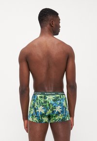 Boxershorts mit einem Muster aus grünen und blauen Palmen, dazu ein kontrastierender schwarzer Bund mit der Aufschrift "BJÖRN BORG". Weicher Stoff.
