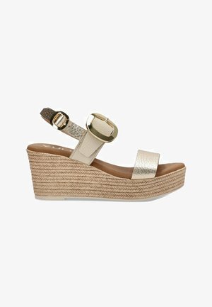 Sandalia de cuña beige con parte superior texturizada, detalle de hebilla dorada y tacón de yute trenzado. Cuenta con una plantilla de cuero suave y correa ajustable.