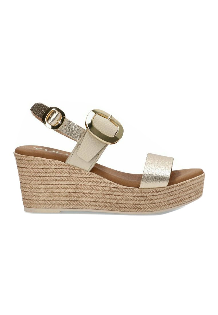 Sandalia de cuña beige con parte superior texturizada, detalle de hebilla dorada y tacón de yute trenzado. Cuenta con una plantilla de cuero suave y correa ajustable.
