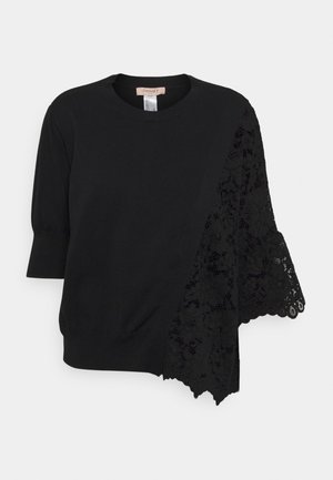 Schwarzer Kurzarm-Pullover mit rundem Ausschnitt, der ein asymmetrisch von einer Schulter herabhängendes, florales Spitzenpaneel aufweist.