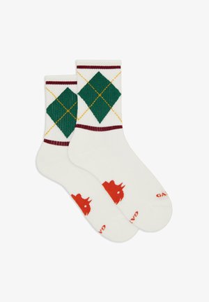 Calze bianche alla caviglia con motivo argyle verde e giallo sui polsini e logo a corona rossa vicino alle dita.