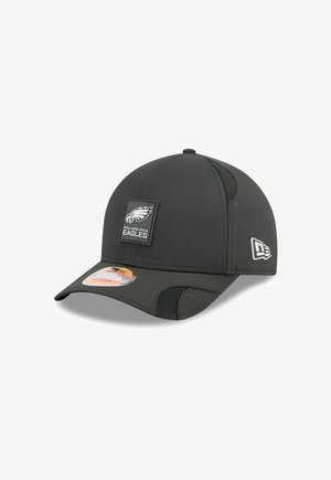 Black baseball cap with a curved visor, textured fabric, side mesh panels, and a Philadelphia Eagles logo patch on the front.