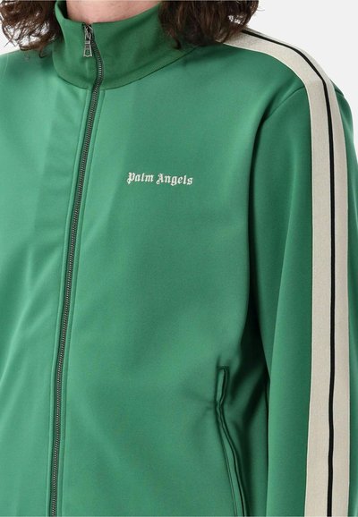 Giacca a vento verde con colletto alto, strisce nere e crema sulle maniche, chiusura con zip e logo "Palm Angels" in bianco sul petto.