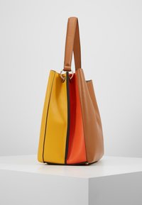 Bolso de cuero con forma triangular, paneles en amarillo, naranja y marrón, y un asa superior con detalles en dorado. Superficies texturizadas.