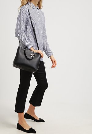 Černá kabelka s kulatým logem, pruhovaná košile na knoflíky, černé zkrácené kalhoty a baleríny s mašlí.