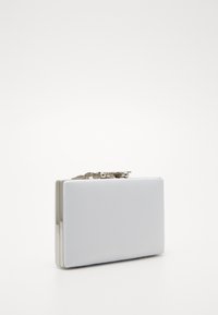 Bílá obdélníková clutch kabelka se stříbrným kovovým rámem a dekorativním stříbrným řetízkem na horní části, na bílém pozadí.