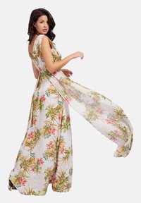 Abito lungo con stampa floreale in colori pastello. Realizzato in tessuto leggero, presenta un design fluttuante e drappeggi laterali regolabili.