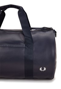 Borsa duffle navy realizzata in materiale resistente, dotata di manici doppi, chiusura con zip e un accento di logo bianco sul lato.