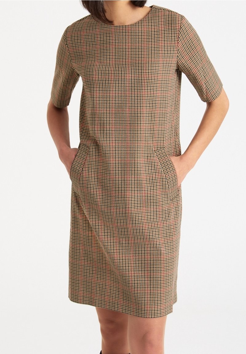Robe à manches courtes avec un motif à carreaux marron et rouge, dotée d'un col rond et de poches latérales, confectionnée dans un tissu lisse et texturé.