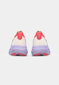 Achteraanzicht van sportschoenen met een witte bovenkant, paarse middenzool, rode accenten en een gestructureerde loopzool voor grip.