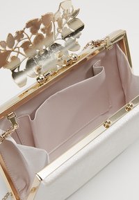 Pochette in raso argento con chiusura in metallo dorato arricchita da intricati motivi floreali; foderata con tessuto rosa liscio; include tasche interne.