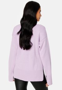 Maglione oversize di un leggero colore viola con orlo a coste e fessure laterali. Tessuto a maglia morbida, con spalle scese e maniche lunghe.