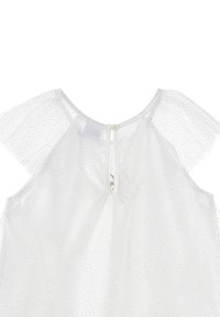 Blusa blanca con mangas de tul transparente con puntos. Cuenta con un corte en la espalda con un botón y delicados acentos plateados.