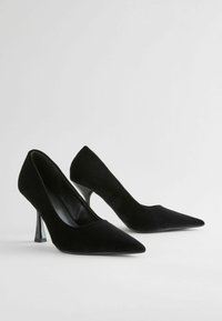 Czarne, aksamitne czółenka na wysokim obcasie z szpiczastym noskiem, charakteryzujące się elegancką sylwetką i błyszczącymi czarnymi obcasami typu stiletto. Brak widocznych zapięć.
