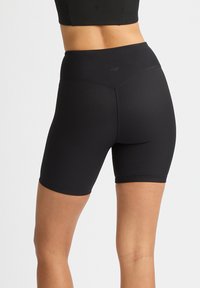 Shorts sportivi neri a vita alta realizzati in un tessuto elasticizzato a coste, con una vita liscia e design che arriva a metà coscia.