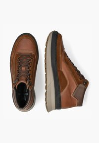 Bottines en cuir marron avec lacets, textures contrastées, semelle en caoutchouc épaisse et accents beiges sur la semelle intermédiaire.