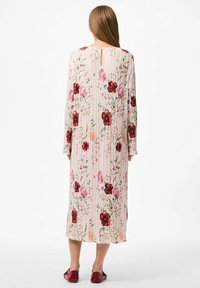 Duga, plisirana haljina u svijetlo ružičastoj boji s crvenim i ljubičastim cvjetnim uzorkom. Sadrži detalj u obliku keyhole oko vrata i dugačke rukave, uparen s crvenim cipelama.