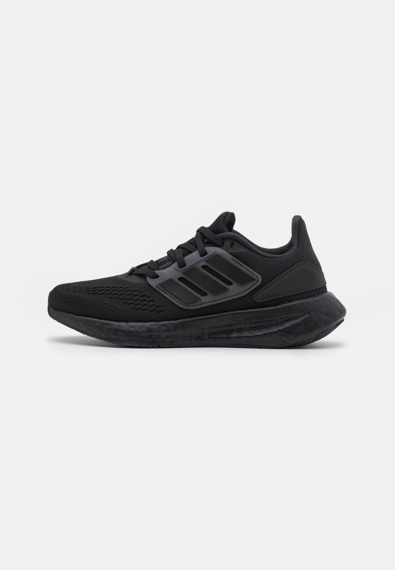 Baskets de sport noires avec tige en mesh, semelle rembourrée et logo noir à trois bandes sur le côté, présentées en profil sur fond blanc.
