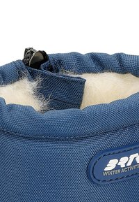 Blauw getextureerde stof met een witte fluffy voering aan de bovenkant, voorzien van een zwarte sluiting en een logo patch dat winteractiviteiten aangeeft.