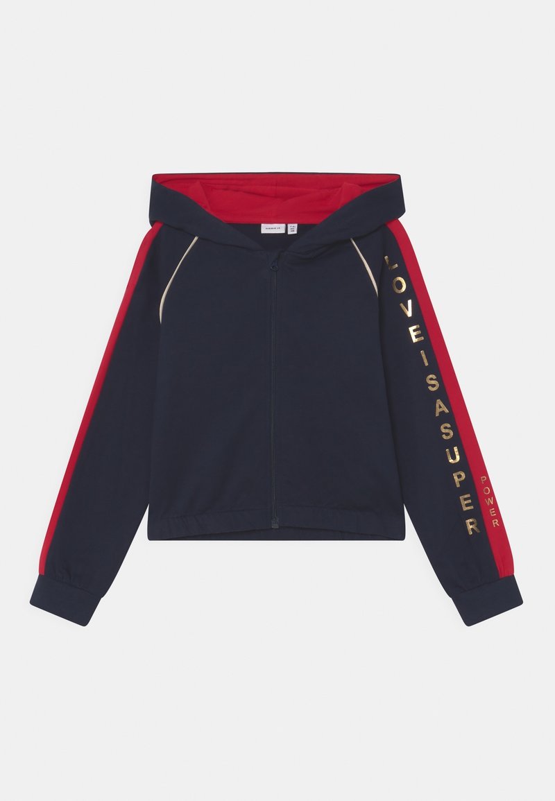 Sweat à capuche zippé bleu marine avec des bandes rouges sur les manches, intérieur de la capuche rouge, et texte doré "LOVE IS A SUPER POWER" sur la manche droite.