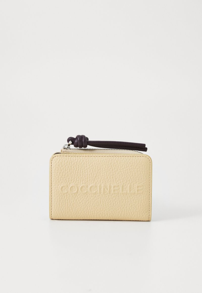 Portefeuille en cuir jaune avec une finition texturée, logo en relief, et un tirette de fermeture éclair violet foncé avec un détail en nœud. Forme rectangulaire compacte.