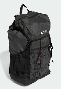 Black patterned backpack with mesh side pockets, adjustable straps, and an orange accent cord. Features a flap top and branded logo.