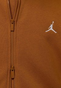 Felpa con cappuccio marrone con cerniera, dalla texture liscia, con una cerniera rialzata e il logo Jumpman bianco sul lato sinistro del petto.