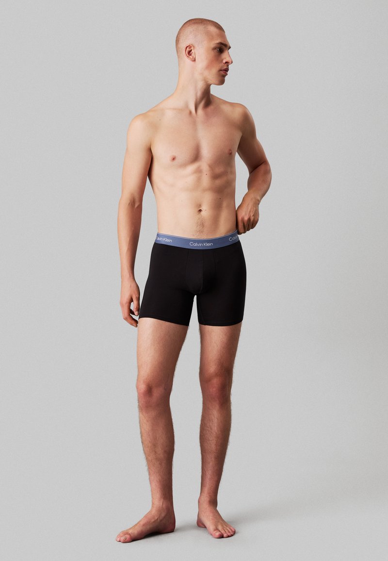 Fekete boxer alsónemű szürke Calvin Klein derékrésszel. Az anyag simának és rugalmasnak tűnik, szoros illeszkedésre tervezve.