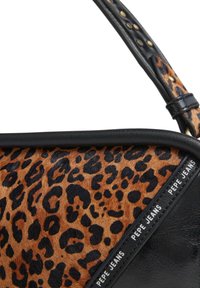 Roja torba z vzorcem leoparda, s črnimi usnjenimi robovi in trakom, z blagovno znamko "PEPE JEANS" na črnem pasu blizu roba.