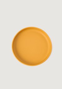 Kerek, lapos, matt sárga kerámiatányér, sima felülettel és enyhén kiemelkedő szélekkel. Minimalista dizájn, minta és díszítések nélkül.