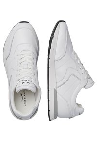Weiße Sportsneaker mit einem glatten, synthetischen Obermaterial, runder Zehenpartie, strukturiertem Sohlenbereich und Schnürsenkeln. Sie verfügen über eine schwarze Außensohle und subtile Branding-Details.