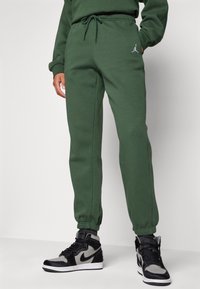 Gröna sweatpants i mjukt material med elastisk midja och dragsko. Inkluderar en liten vit Jordan-logotyp på vänster lår.