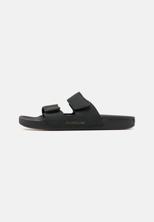 Mustad must sandaalid kahe reguleeritava Velcro rihmaga, kummist põhi ja kõrgendatud logo detailiga. Valmistatud sametise sarnase materjaliga ja tasase disainiga.