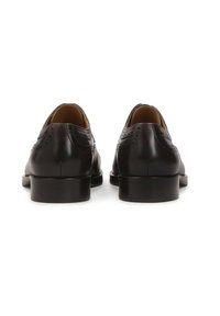 Pantofi din piele neagră cu o textură netedă, având detalii brogue și un toc jos. Vederea din spate evidențiază finisajul lustruit.