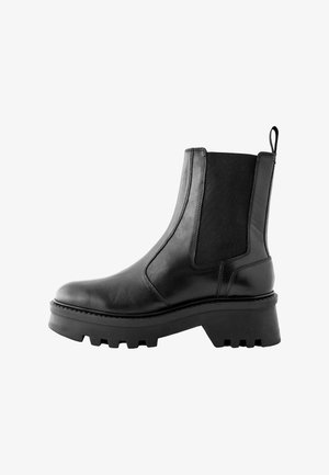 Bottine en cuir noir avec des panneaux élastiques sur les côtés, une semelle en caoutchouc épaisse et une languette à l'arrière pour un enfilage facile. Texture lisse et couture minimaliste.