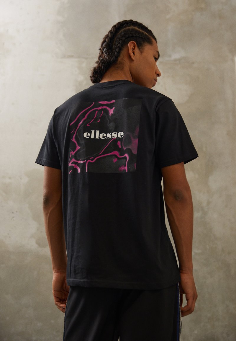 Black t-shirt featuring a stylized pink and black graphic and "ellesse" logo on the back. Short sleeves and casual fit.