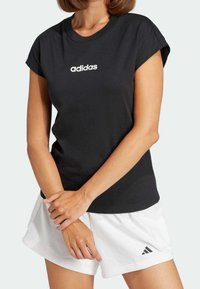 Black short-sleeve t-shirt with white "adidas" logo on the front, paired with white shorts featuring a small black logo on the hem.
