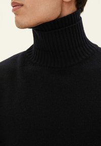 Maglione a collo alto nero in maglia con texture a coste, collo alto e design aderente, che mette in mostra una finitura del tessuto liscia.