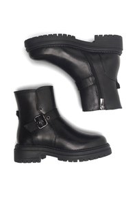 Czarne skórzane botki za kostkę z grubą, bieżnikowaną podeszwą, bocznym zamkiem oraz dekoracyjnym paskiem z klamrą na białym tle.
