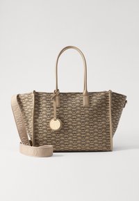 Beige tygväska med präglat logomönster, strukturerad form, dubbla handtag och en avtagbar rem. Har en liten rund logocharm.