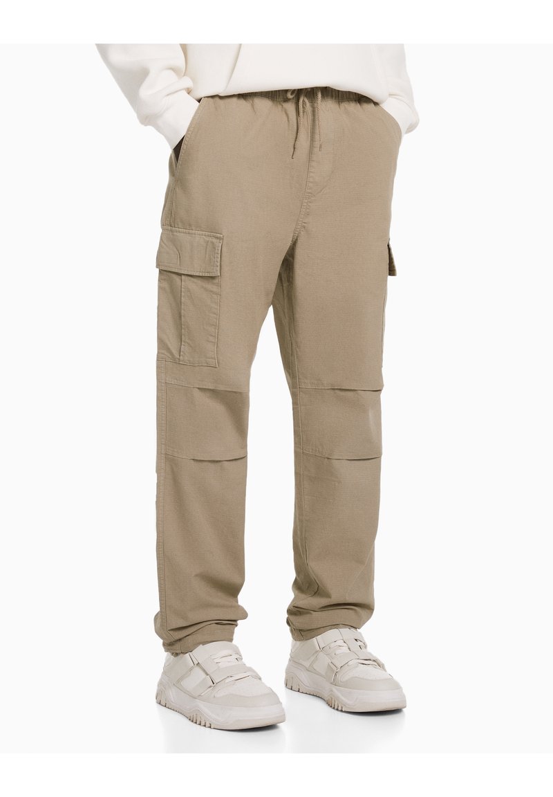 Khaki cargo kalhoty s páskem na stažení, několika bočními kapsami a volným střihem. Vyrobeno z lehké tkaniny, poskytující neformální design.