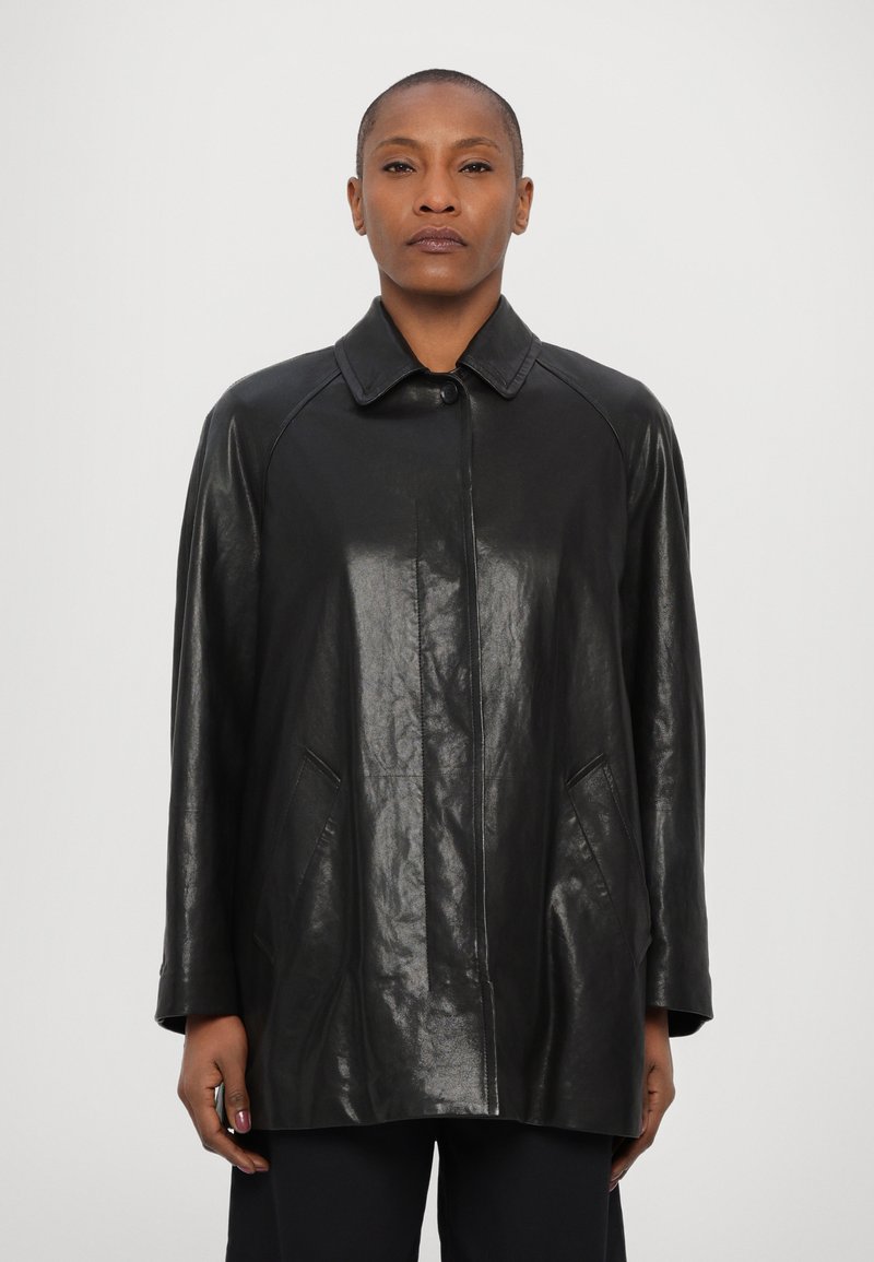 Cappotto in pelle nera con finitura lucida, dotato di colletto, chiusura anteriore con bottoni e due tasche laterali. Maniche a taglio dritto.