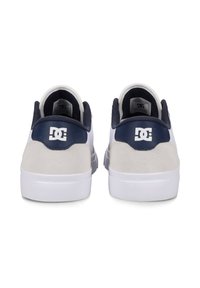 Weiße Sneaker mit navyfarbenen Akzenten, weichem Wildlederschaft, Gummisohle und DC-Logo auf der Rückseite. Verfügt über einen gepolsterten Kragen und eine glatte Textur.