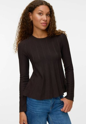 Langwerpige mouwen, geribbeld zwart top met een ronde halslijn en een uitlopende zoom, gecombineerd met blauwe jeans. Zachte textuur en comfortabele pasvorm.